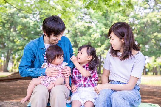 新緑の公園で遊ぶ家族4人。幸せ、愛情イメージ