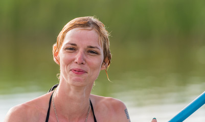 Head shot of a Female Model Paddler Sitting on a Stand Up Paddle Board on a Still Lake