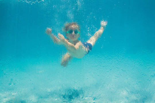 Boy having fun playing underwater in swimming pool on summer vacation