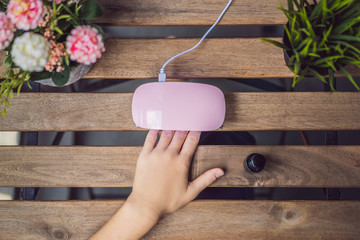 Young woman makes manicure with gel polish and UV lamp in pink shades
