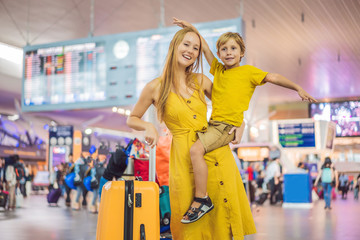 Family at airport before flight. Mother and son waiting to board at departure gate of modern international terminal. Traveling and flying with children. Mom with kid boarding airplane. yellow family