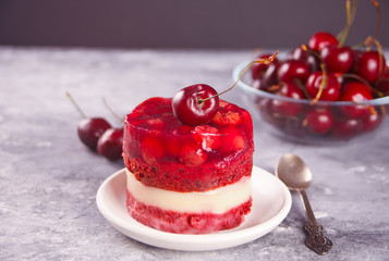 Homemade cherry cake with vanilla cream and cherry jelly on the gray background
