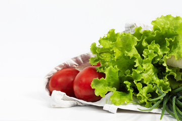 Vegetables and green products in a cotton bag on a white background with copy space