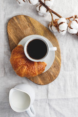 Cup of black coffee with croissant and milk on  table. The concept of breakfast, flat lay, top view.