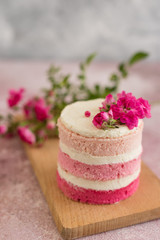 Beautiful pink cream and berries cake on a light concrete background. Birthday celebration
