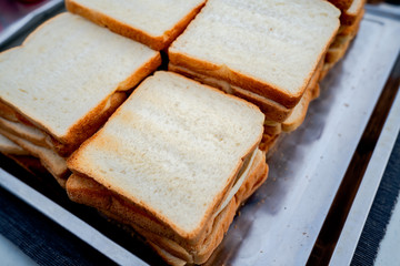 Thin toasted white bread Many are placed in trays ready to eat.