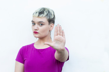 Young blond woman doing ok sign with fingers, showing hush sign with serious expression,showing stop gesture, excellent symbol, isolated over white background