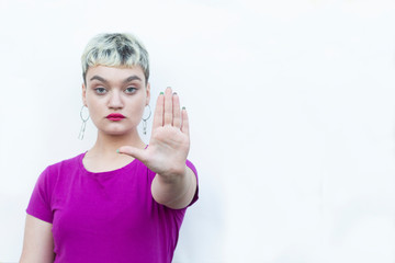 Young blond woman doing ok sign with fingers, showing hush sign with serious expression,showing...