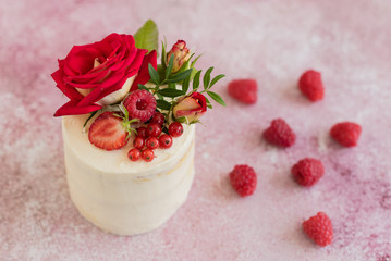 Beautiful pink cream and berries cake on a light concrete background. Birthday celebration