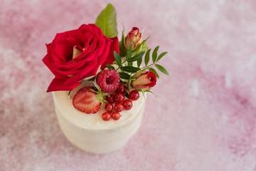 Beautiful pink cream and berries cake on a light concrete background. Birthday celebration