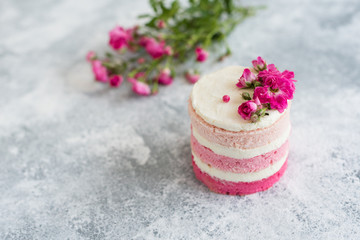 Beautiful pink cream and berries cake on a light concrete background. Birthday celebration