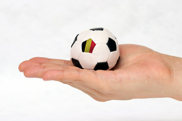 Fototapeta premium Mini football in hand and one black point of football is Belgium flag.