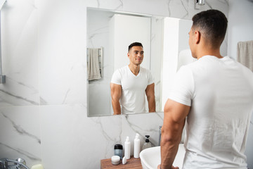 Back side of smiling young man looking at mirror