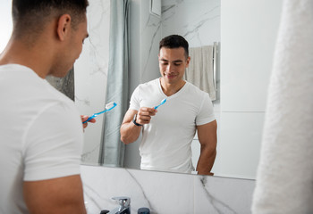 Young smiling man with tooth brush in bathroom