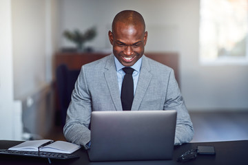 Smiling African American businessman using a laptop at work