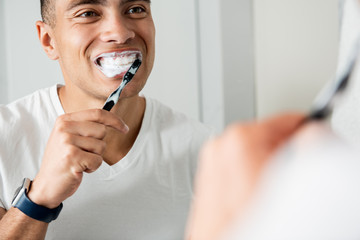 Close up of young brunette man brushing teeth