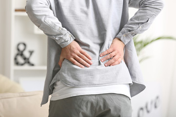 Young man suffering from back pain at home