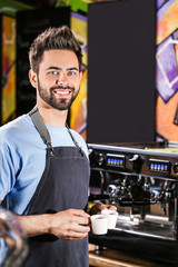 Young barista with cups of hot coffee in cafe