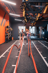Trainer and overweight woman using TRX straps for cardio