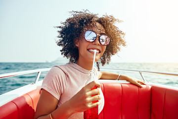 Smiling woman sipping on a drink while out sailing