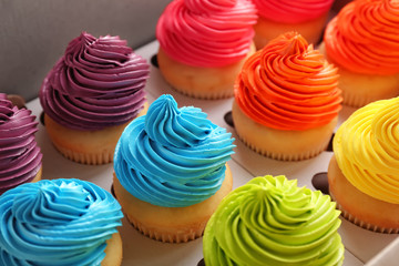 Many tasty colorful cupcakes in box