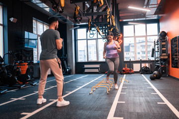 Obraz na płótnie Canvas Overweight woman having obstacle race in gym with her trainer