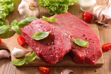 raw beef piece with basil on board