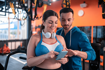 Dark-haired woman showing her old photos to her trainer