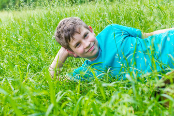 happy teen boy lying in the grass in summer