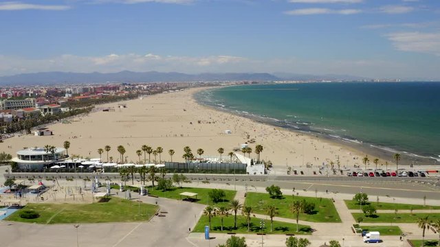 Aerial side view along Valencia city beach and seaside tourist leisure area on a beautiful bright sunny day, 4k drone long video