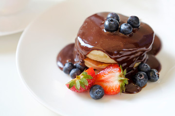 Pancakes with chocolate and blueberry on the top; healthy summer breakfast
