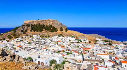 Small whitewashed village of Lindos with Acropolis at foot of mountain. Scenery of Rhodes island at...