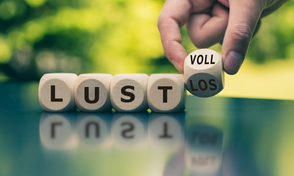 Lustvoll oder Lustlos" Hand dreht einen W&uuml;rfel und &auml;ndert das Wort "lustlos" in "lustvoll".