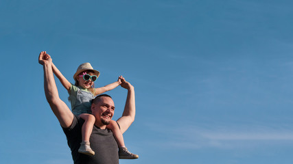 father and daughter on shoulders happily rejoice. dad holding little daughter sitting on the flight...