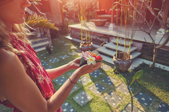 Woman holding canang sari - offering for Gods and praying. Balinese tradition.