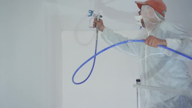 beauty slow motion. repair of the apartment - professional painter paints the walls with white paint spray gun