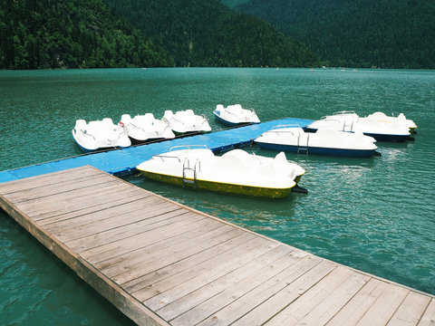 Group of anchored white catamarans at blue lake background. Water pedal boats