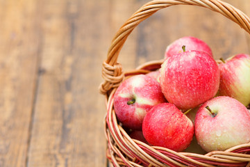 Red apples in wicker basket on wooden boards