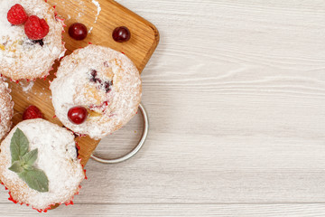 Homemade fruit muffins sprinkled with powdered sugar on board.