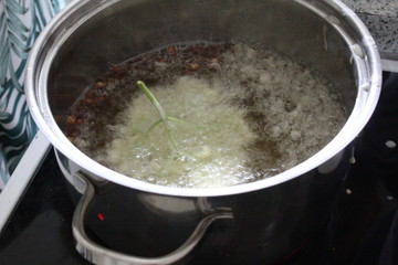elderflowers in dough coat getting deep fried in pot in kitchen