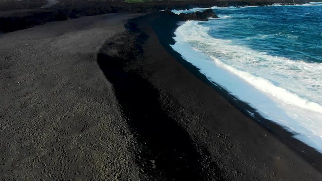 fast aerial shot over black sand beach near former kapoho bay and cape Kumukahi on the east side of the big island. the new black sand beach is made from hot lava shattering on contact with the ocean