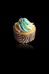 Color full of butter on vanilla cup cake with reflection on black background.