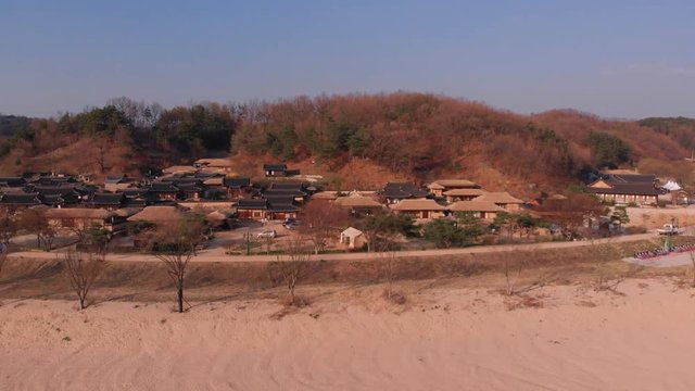 Aerial gentle tilt down rise up in front of Korean traditional village