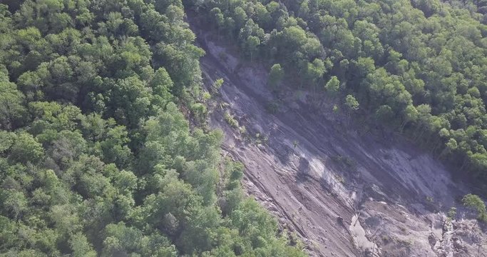 Smooth rotating aerial drone shot of a large, 20+ acre landslide on a steep forest slope, with downed trees and mud visible to the river.