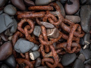 A rusted old chain half buried in pebbles on a beach in Devon, UK