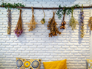 Various vintage colorful dried flowers hanging on white brick wall