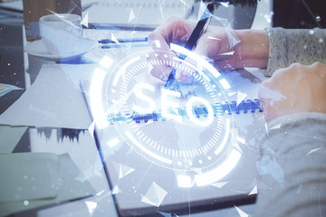 Multi exposure of woman's hands making notes with SEO icon. Concept of Search engine optimization