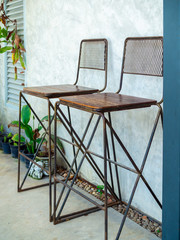 Two iron and wooden bar stools on cement wall background