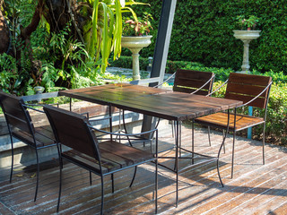 Wooden chairs and wooden table on wooden floor near the green garden