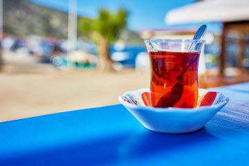 Turkish tea in traditional tea glass on the blue wooden table of an Aegean outdoor cafe